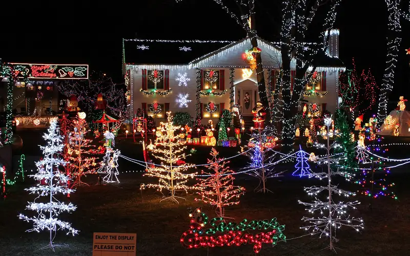 A house covered in colorful Christmas lights and lit trees at night